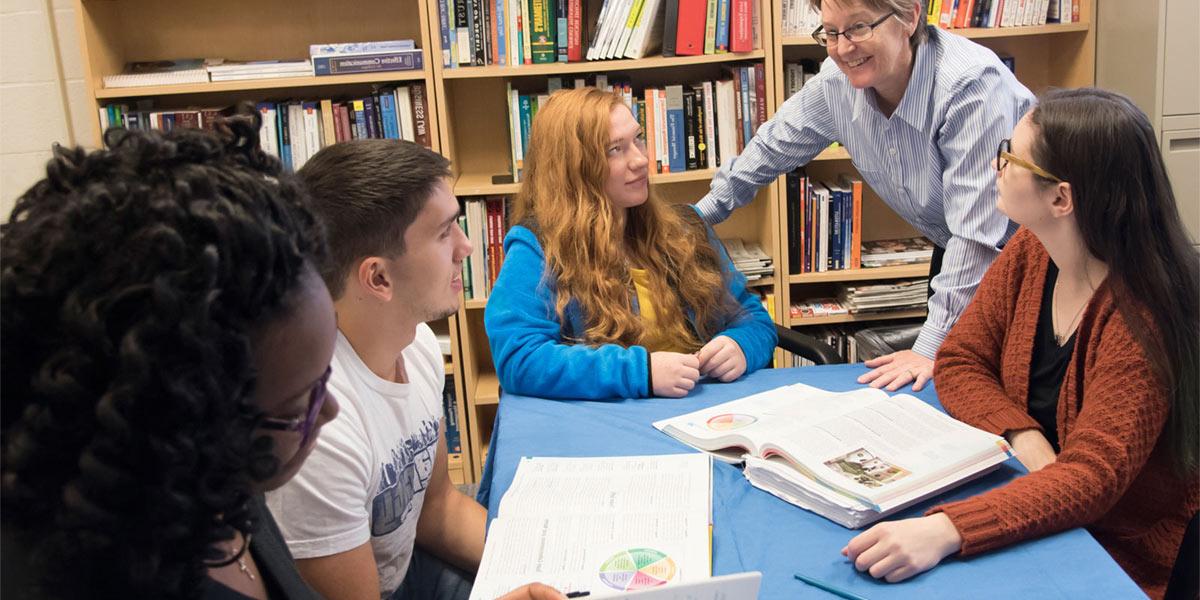 Professor checking in with students studying.